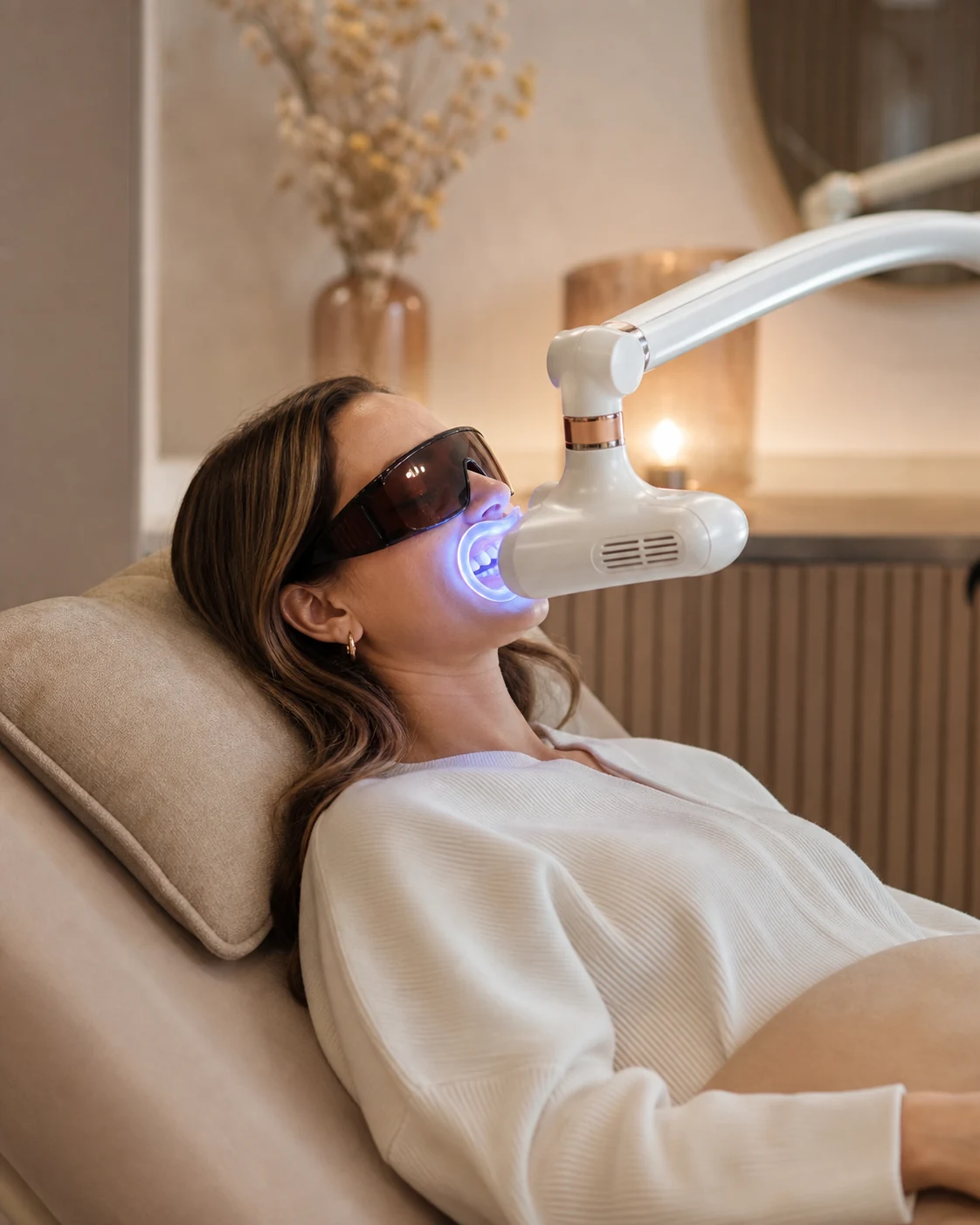 Kosmetische Zahnaufhellung mit Aufhellungsgel und LED-Lampe in warmer Salonatmosphäre